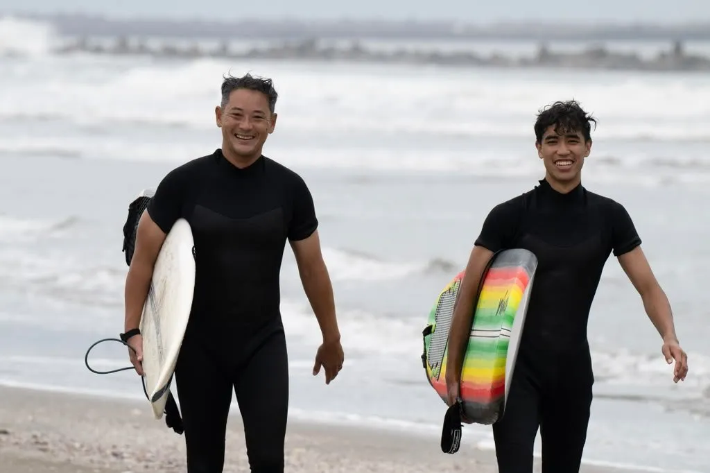 ボードを抱えて笑顔で海から上がってくる広輔（左）とゲスト